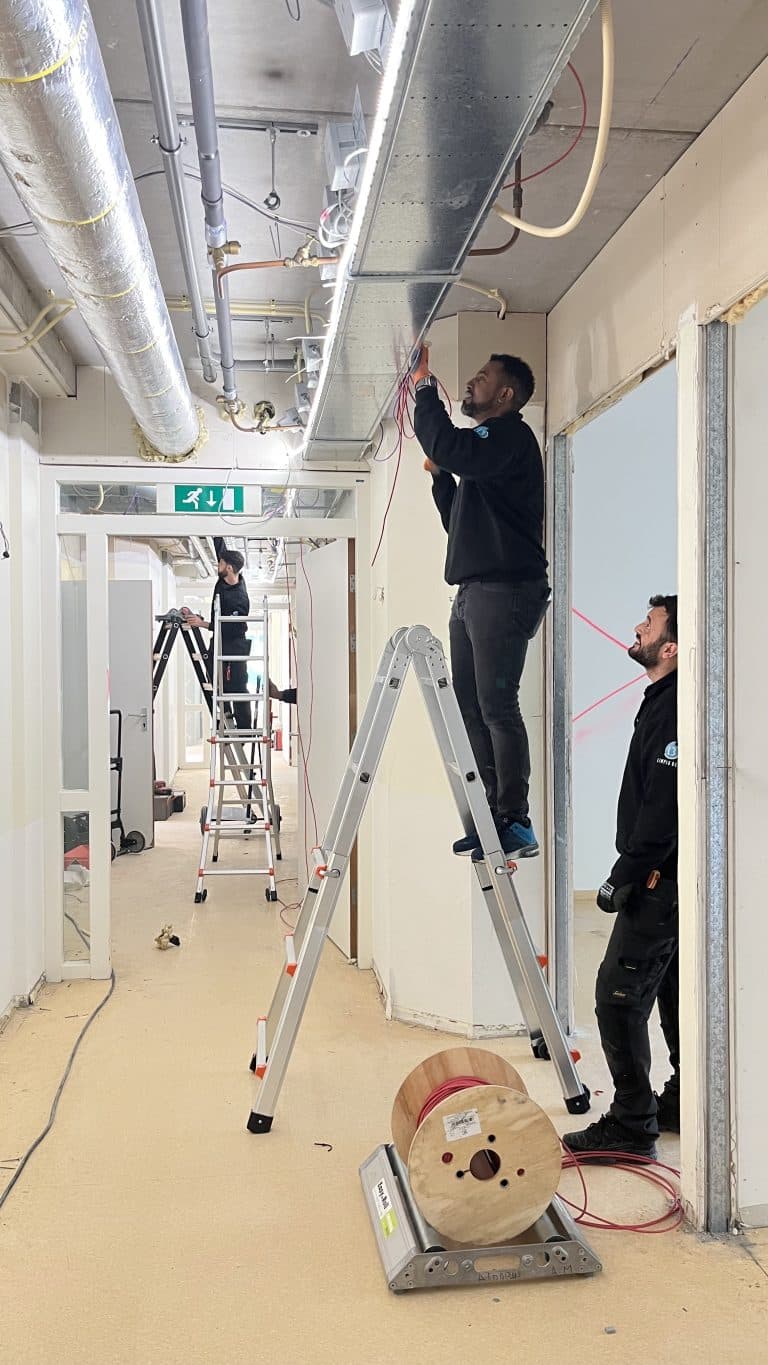 Monteurs aan het werk op een ladder in een gang